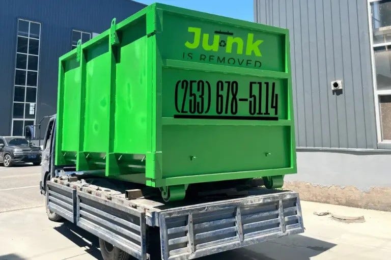 Bright green junk removal dumpster loaded on a flatbed truck outside a commercial building, showcasing professional junkisremoved services.